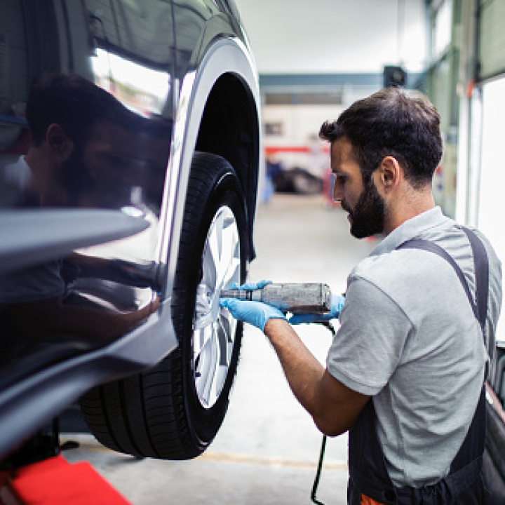 Mecánico revisando la rueda de un coche eléctrico en un taller.