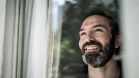 Mature man looking through window at home